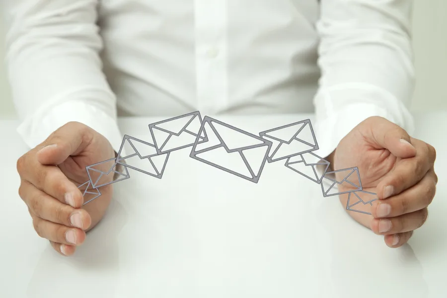 Mains encadrant des pictogrammes d'enveloppes, symbole de la transmission sécurisée d'un fichier d'adresses