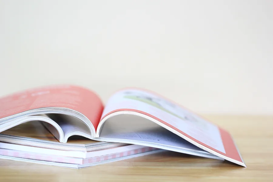 Magazines brochés empilés sur une table, le premier ouvert