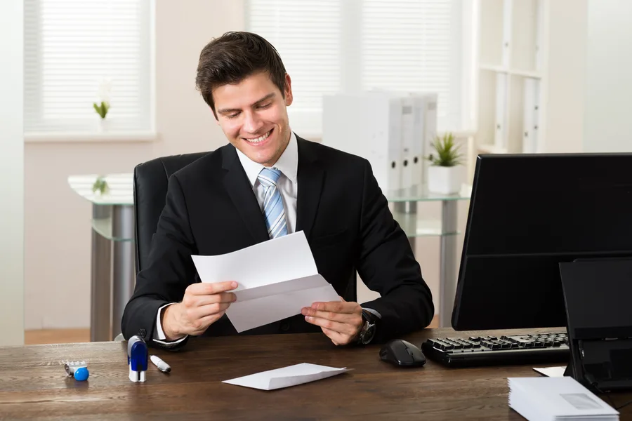 Dirigeant lisant à son bureau un courrier de prospection qui lui est adressé nominativement